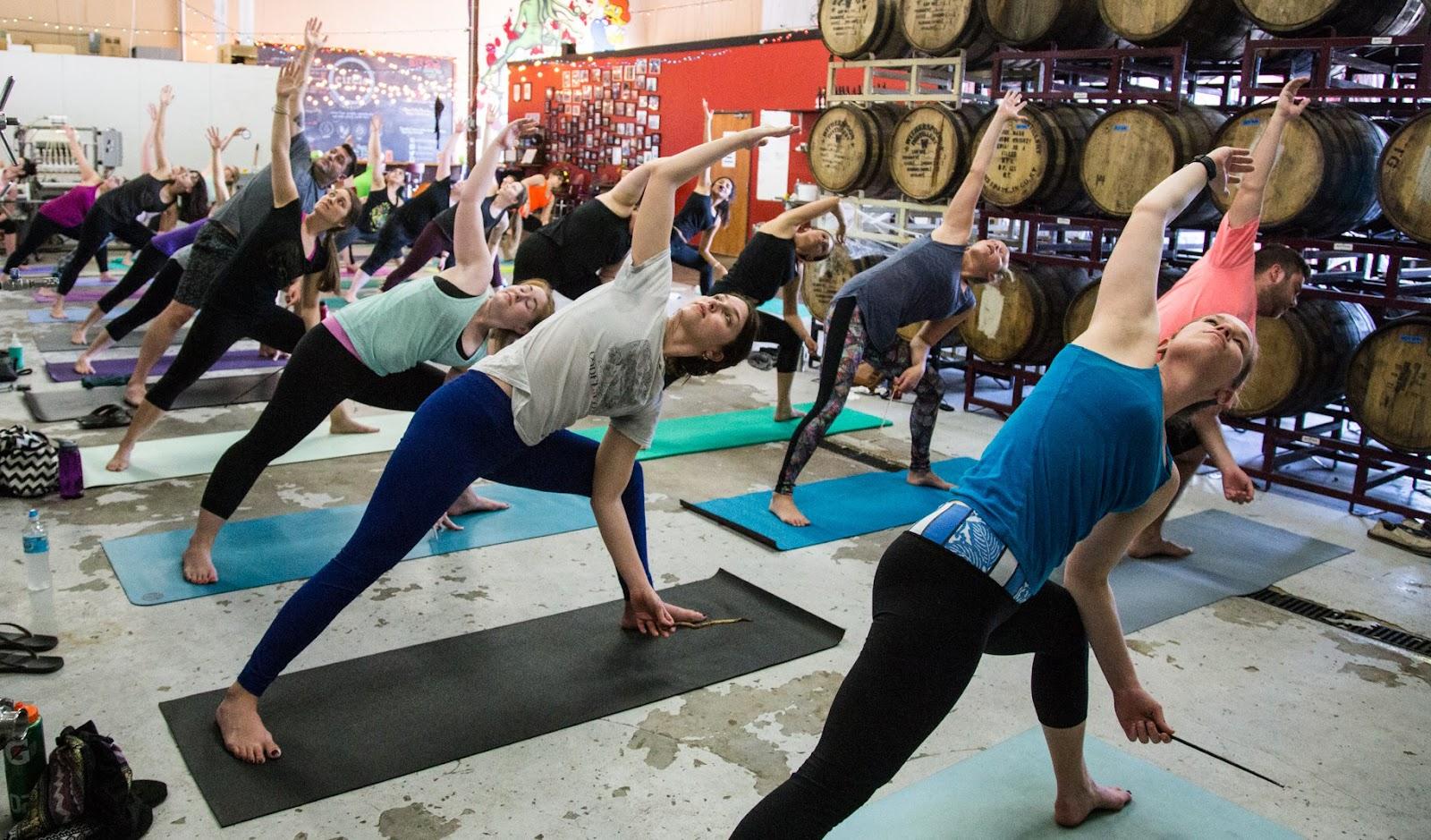 A group of women gracefully practicing yoga in the vibrant ambiance of a brewery, creating a harmonious blend of relaxation and social enjoyment. The serene setting captures the essence of wellness and community in a unique brewery experience.